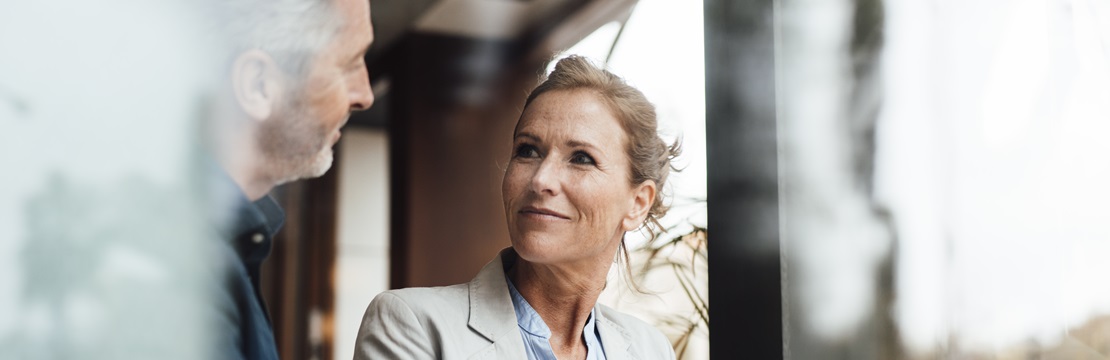 Smiling businesswoman with businessman in cafe seen through glass